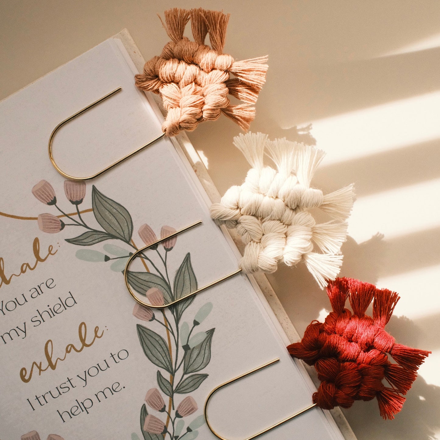 Open book with decorative bookmarks and floral design on a neutral background